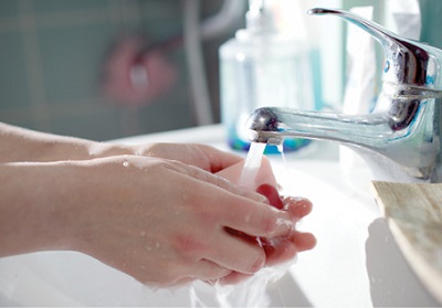 close up of a woman washing her hands with soap and water in the bathroom