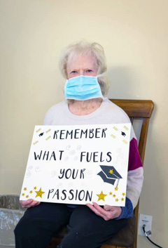 Shady Lawn female Resident holding up a sign that says Remember What Fuels Your Passion as a note to graduating high school seniors