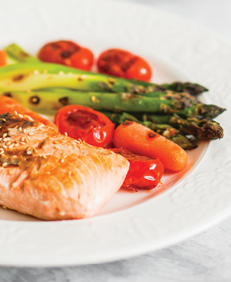 plated fish with baby carrots cherry tomatoes and grilled asparagus