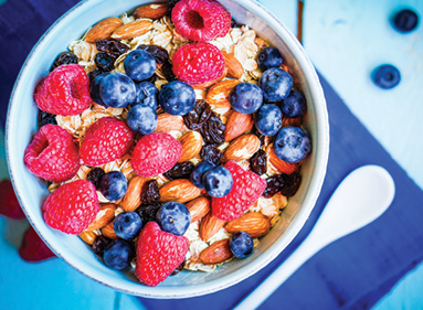 top view large bowl of oatmeal dressed with berries and almonds